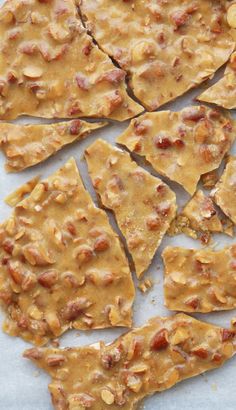 crackers with peanut butter and peanuts on them sitting on a piece of parchment paper