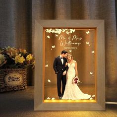 a wedding photo frame with the bride and groom in front of it, surrounded by flowers