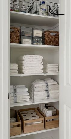 an organized closet with folded white towels and baskets on the bottom shelf in front of it