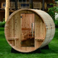 a wooden barrel sauna in the grass