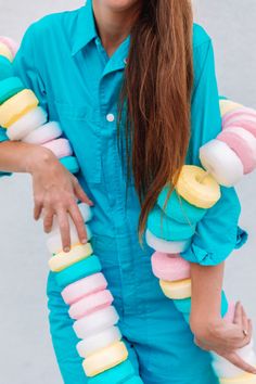 a woman with long brown hair wearing blue jumpsuits and holding ice cream pops