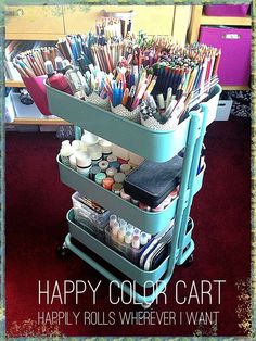 a cart filled with lots of paint and pencils on top of a red carpet