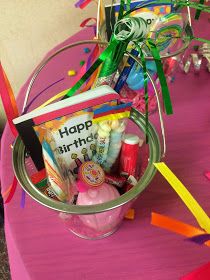 a pink table topped with a bucket filled with lots of toys and confetti