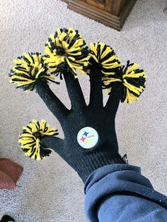 a person's hand with black and yellow pom - poms on it