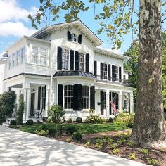 a large white house with black shutters on the front and side windows is shown