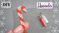 a hand holding a candy cane with snowflakes on it and a bead christmas ornament next to it