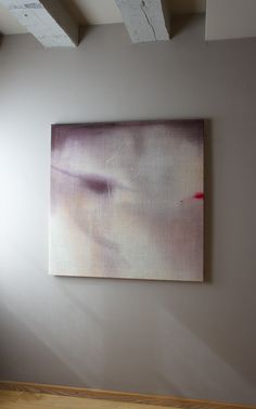 an abstract painting hangs on the wall next to a wooden floor and white painted ceiling