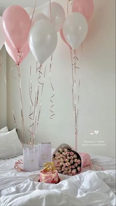 pink and white balloons are hanging from the ceiling above a bed with a bouquet of flowers