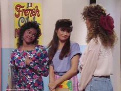 three young women standing in front of a poster