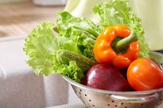 a metal colander filled with lots of fresh vegetables