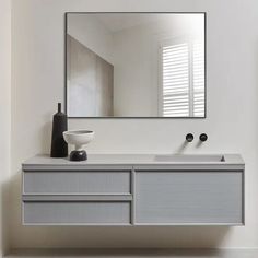 a bathroom with a sink, mirror and vase on the counter top in front of it