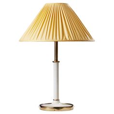 a white lamp with a gold shade on it's base and a light bulb in the middle