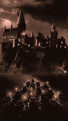 hogwart's castle lit up at night with candles floating in the water below