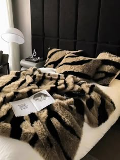 a bed with black and white fur on it's headboard next to a lamp