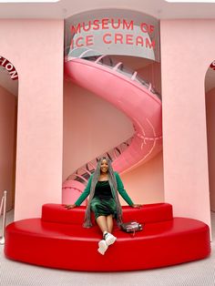 a woman sitting on a red couch in front of a museum of ice cream sign