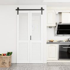 a kitchen with white cabinets and an open door leading to the dining room, next to a black stove top oven