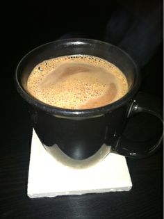 a cup of coffee sitting on top of a white napkin