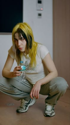 a woman with yellow hair is holding a water bottle