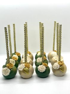 seven green vases with gold and white flowers on them are sitting side by side