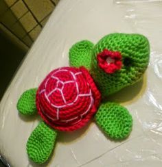 a crocheted turtle sitting on top of a toilet