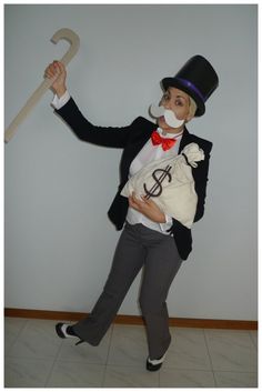 a man in top hat and bow tie holding an umbrella while standing next to a wall