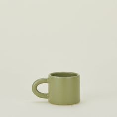 a green mug sitting on top of a white table