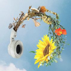 a vase with flowers and headphones hanging from it's side in the air