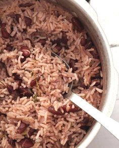 a pot filled with rice and beans on top of a table next to a spoon