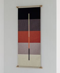 a wall hanging on the side of a white wall with an orange and black stripe