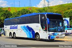 a blue and white bus is parked on the side of the road in front of other buses