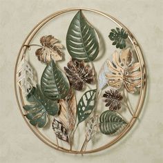 a circular metal wall decoration with leaves and flowers on the side, mounted on a beige wall