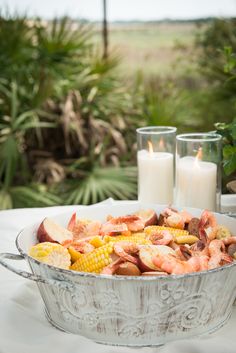 a large metal pan filled with food on top of a table next to two candles