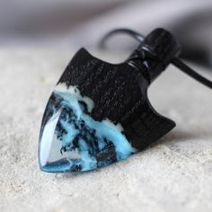 a black and white pendant with blue swirls on it's side sitting on the sand