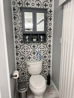 a white toilet sitting in a bathroom next to a wall mounted cabinet and towel dispenser