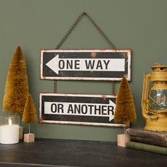 one way or another sign hanging on a wall next to a candle and some books