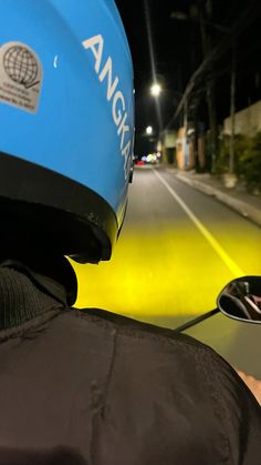 a person wearing a blue helmet is riding a motorcycle down the street at night time