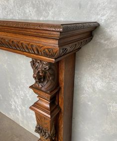 an ornate wooden mantle with carvings on the top and bottom, against a white wall