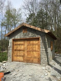 two garages built into the side of a stone building with wood doors and windows