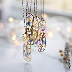 three necklaces with flowers on them are hanging from the table next to some candles