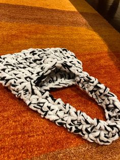 a black and white scarf laying on top of an orange rug