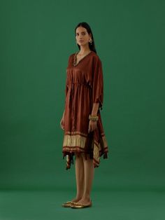 Satin Lagdi Patta Kaftan featuring a round neck with V-cut, elbow-length sleeves, a front tie-up, shoulders embellished with ghungroos, silk thread tassel at the waist, and lagdi patta at the hem. Fabric: Modal Satin Color: Brown Note: Available in other colors The product will be delivered within 20-25 days of the order placed Wash care - Dry clean only Size Measurements: XS S M L XL 2XL Waist 24 26 28 30 32 34 Bust 32 34 36 38 40 42 Hips 34 36 38 40 42 44 Satin Kaftan, Brown Note, Satin Color, V Cut, Silk Thread, V Cuts, Elbow Length Sleeve, Best Deal, Ready To Wear