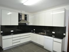 an empty kitchen with white cabinets and black counter tops is seen in this image from the front view