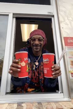 a man holding two red cups in front of his face and smiling at the camera