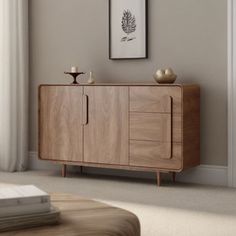 a living room with a wooden cabinet next to a window and pictures on the wall