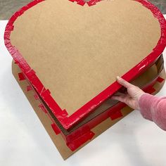 a cardboard heart shaped box being held by a hand