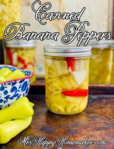 two jars filled with canned banana peppers on top of a table next to bowls and spoons