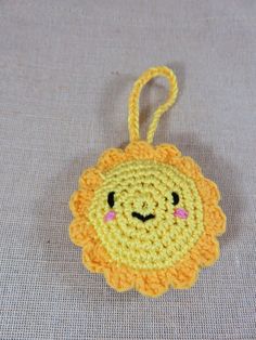 a crocheted lion ornament hanging from a hook on a gray surface