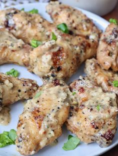 chicken wings covered in sauce and garnished with green leaves on a white plate