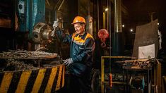 a man standing next to a machine in a room filled with metal items and machinery