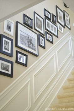 a staircase with pictures on the wall and framed photos hanging up against the stair rail